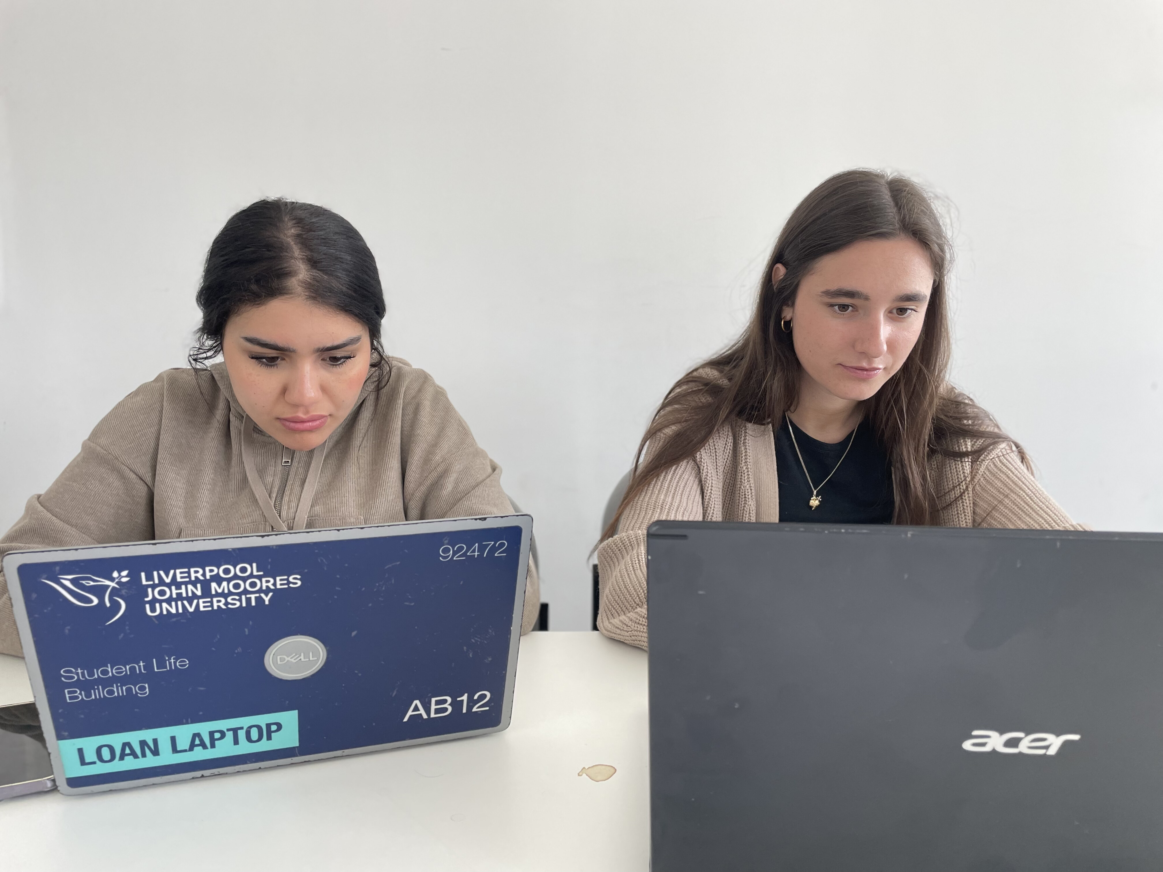 Two people working side by side on laptops
